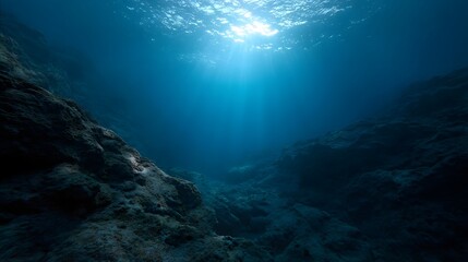 Sunlight filtering through deep blue ocean waters onto submerged rocky formations