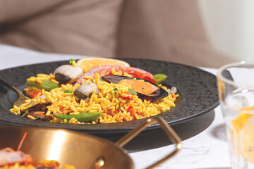 Dinner table with seafood paella and drink in a cozy setting during the evening hours