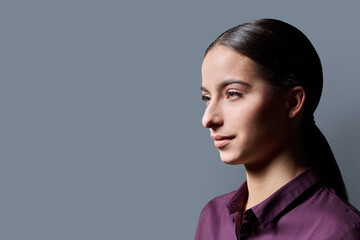 Profile portrait of young smiling woman on gray background © Valerii Honcharuk