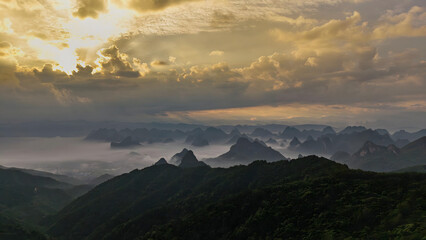 Obraz premium Guilin Mountains at Golden Hour with Misty Peaks and Dramatic Sky