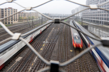 Zurich, Switzerland - October 28, 2024: View from a pedestrian bridge over the tracks at Zurich main station, arriving and departing trains on a gloomy winter day with muted tones.
