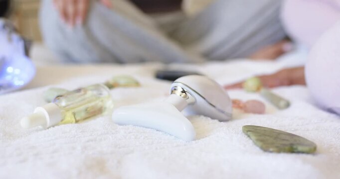 Right hand is moving toward white T-shaped massager on bed towel, starting massage routine with oil