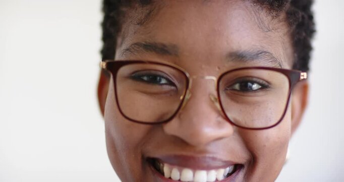 African American woman camera prompt smiling holding gaze at white wall with specs showing warmth