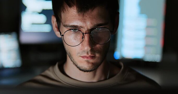 White Caucasian male software developer work late night, program coding in home office. Computer engineering job, data scientist, cybersecurity, information technology. Close-up eyeglasses, handheld