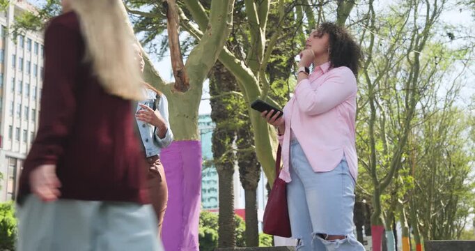 Female pair walking city path right woman checking phone making left woman point at painted trees