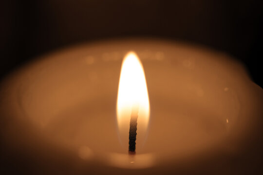 The wick of a burning wide candle in a church