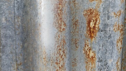 Fototapeta premium Rust Patterns on Galvanized Metal Wall Texture. Galvanized metal wall with scattered rust patches forming abstract industrial grunge texture