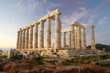 The ancient Greek Temple of Poseidon at Cape Sounion during a vibrant sunset with pink clouds