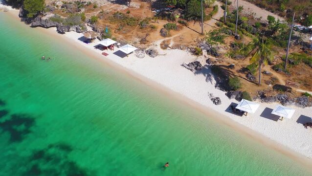 Drone view of long white beach and shallow green-blue water