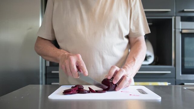 Senior man hands slicing cooked beetroot