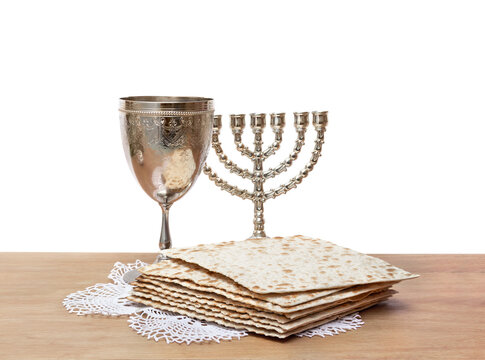 Passover Seder with matzah, wine cup, and menorah on wooden table on white background with copy space for text. Jewish holiday concept
