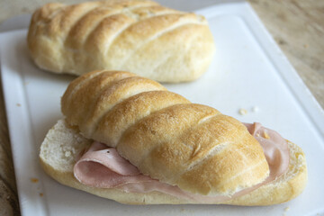 ham sandwich with crusty bread on white cutting board