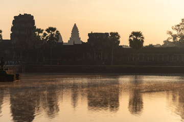 Naklejka premium Angkor Wat, Cambodia, Sunrise behind the iconic Angkor Wat temple. Reflections and mist on lake
