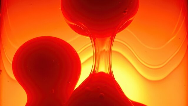 Close up of red lava lamp with flowing wax against glowing orange background