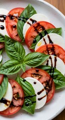 Slices of fresh mozzarella, ripe tomato, and bright basil leaves are drizzled with dark balsamic reduction.