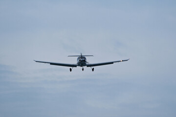 Single-engine plane approaching the airport under a cloudy sky
