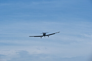 Single-engine plane approaching the airport under a cloudy sky