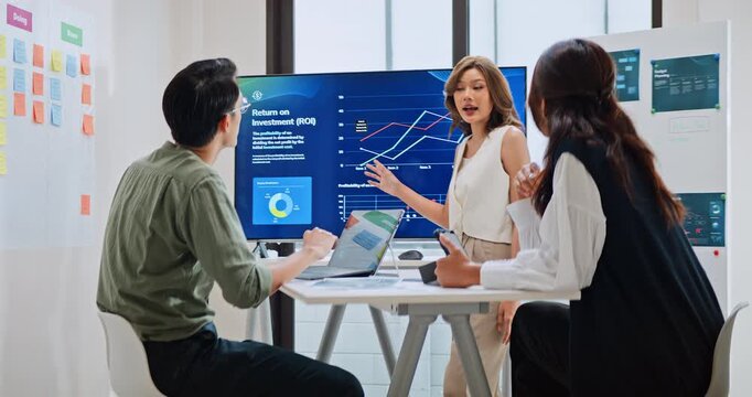 Group of Asian generation z business people work together in home office. Financial team businesspeople brainstorm meeting, use computer and presentation screen monitor. Corporate teamwork concept