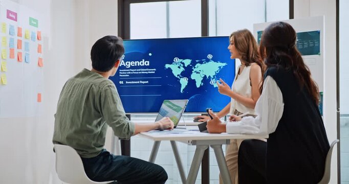 Group of Asian generation z business people work together in home office. Financial team businesspeople brainstorm meeting, use computer and presentation screen monitor. Corporate teamwork concept