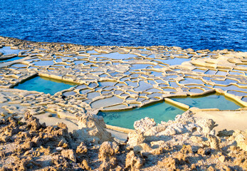 Salt pans with turquoise water near Zebbug on Gozo, geometric patterns in natural coastal surroundings