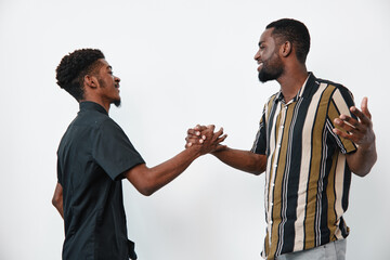 Two black men with dark skin shaking hands and smiling in casual clothes on white background for...