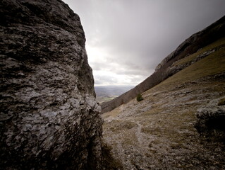 Formazione rocciosa naturale su pendio montano con masso scolpito dal tempo