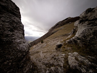 Formazione rocciosa naturale su pendio montano con masso scolpito dal tempo