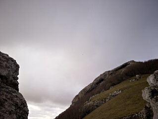 Formazione rocciosa naturale su pendio montano con masso scolpito dal tempo