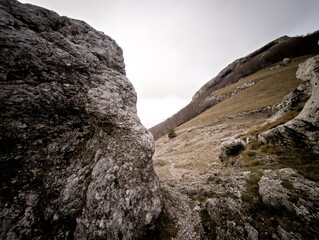 Formazione rocciosa naturale su pendio montano con masso scolpito dal tempo