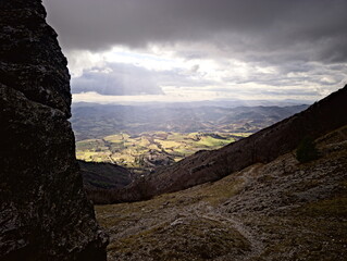 Paesaggio montano, campi coltivati e fiume nella valle illuminata dal sole