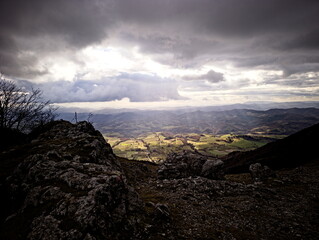 Paesaggio montano, campi coltivati e fiume nella valle illuminata dal sole