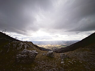 Paesaggio montano, campi coltivati e fiume nella valle illuminata dal sole