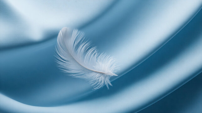 Soft white feather resting delicately on smooth flowing blue satin fabric symbolizing lightness and gentle elegance in minimalistic style