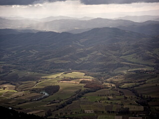 Paesaggio montano, campi coltivati e fiume nella valle illuminata dal sole