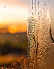 Close-up of fresh water droplets and condensation on glass with warm sunset bokeh background