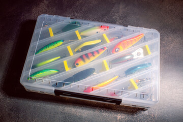Transparent fishing tackle box containing lures hooks bobber. Image for fishing themes © Krievietka