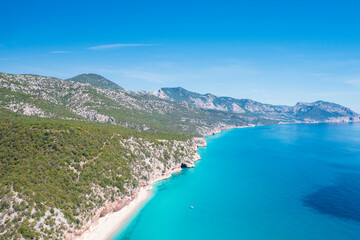 Fototapeta premium Aerial view of Cala Luna beach on the coast of Baunei and Dorgali, Sardinia, Italy. Turquoise water, white sandy shoreline and dramatic limestone cliffs along the Gulf of Orosei.