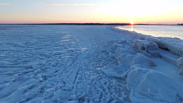 Broad aerial perspective of fractured ice terrain extending into horizon with pastel colored sky