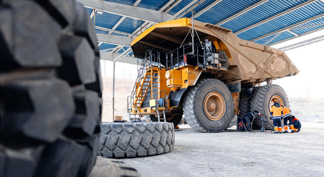 Maintenance fix service of industry truck, banner. Replacing tires on wheels of mining dump car in garage