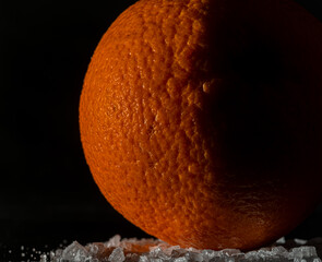 Orange fruit detail with shiny black table and white salt
