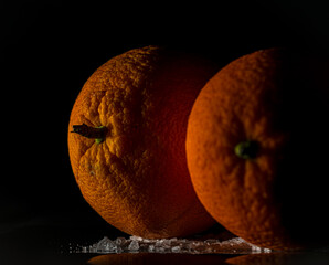 Orange fruit detail with shiny black table and white salt