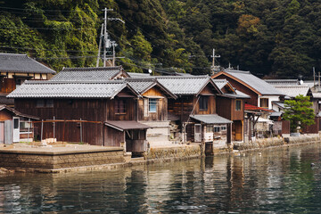 Obraz premium Ine Fishing Village, Kyoto prefecture, Japan, Ine-ura landscape coastal view, Funaya, traditional wooden boat houses, Ine Bay during boat tour cruise, Yoza District, in a autumn fall day