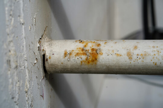 Close-up of rusty metal pipe with peeling paint and corrosion damage