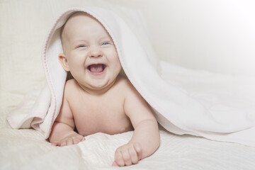 Adorable Laughing Baby Peeking from Under White Blanket with Joyful Expression