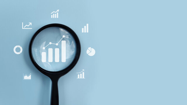 Magnifying glass analyzing business growth charts and data icons, representing analytics, performance tracking, financial analysis, and strategic planning.