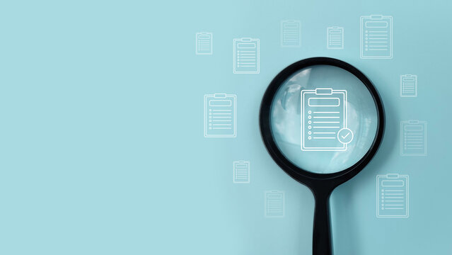 Magnifying glass over checklist document showing audit, compliance review, quality control, and business inspection.