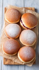 Jam filled fried dough doughnut with powdered sugar on baking paper. Traditional sweet pastry dessert for celebration and snack.