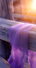 A purple cloth draped over a weathered wooden fence post at sunset, symbolizing Good Friday. The warm light enhances the texture of both fabric and wood