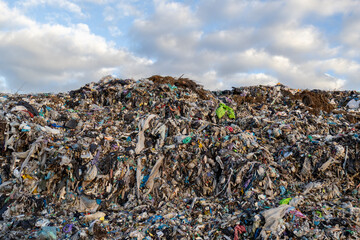 Obraz premium A vast expanse of trash looms under a cloudy sky, highlighting the severe problem of garbage accumulation and ecological impact on our planet