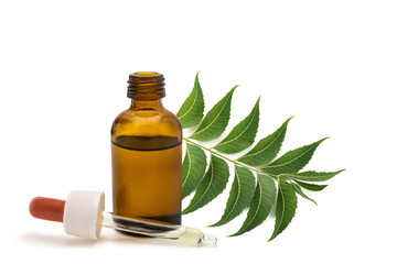 Neem oil extract in glass bottle with dropper and neem leaves branch isolated on white background